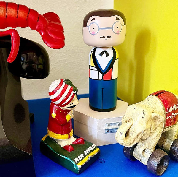 Collection of colorful figurines including a lobster, cartoon character, and bear on a blue surface.